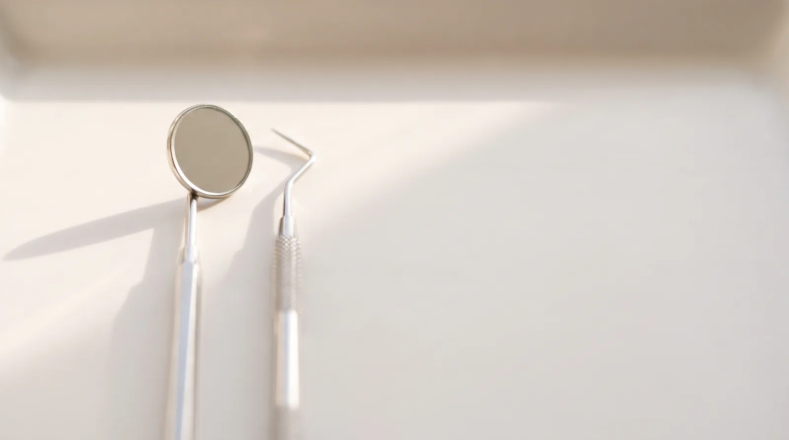 A dental mirror and a dental probe on a white tray