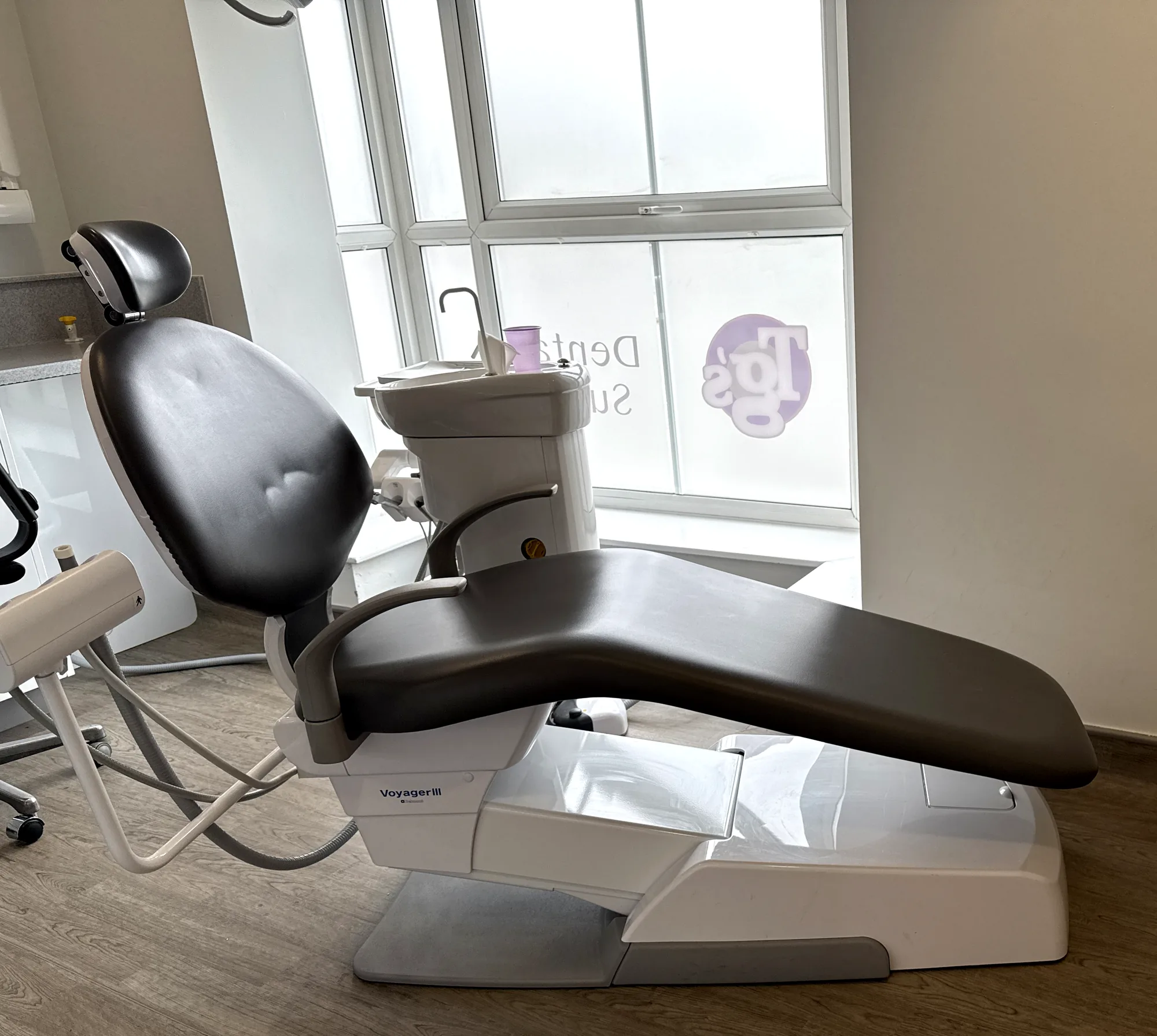 An empty treatment chair at Rugby, beside the window carrying the TG's Dental Suite graphic