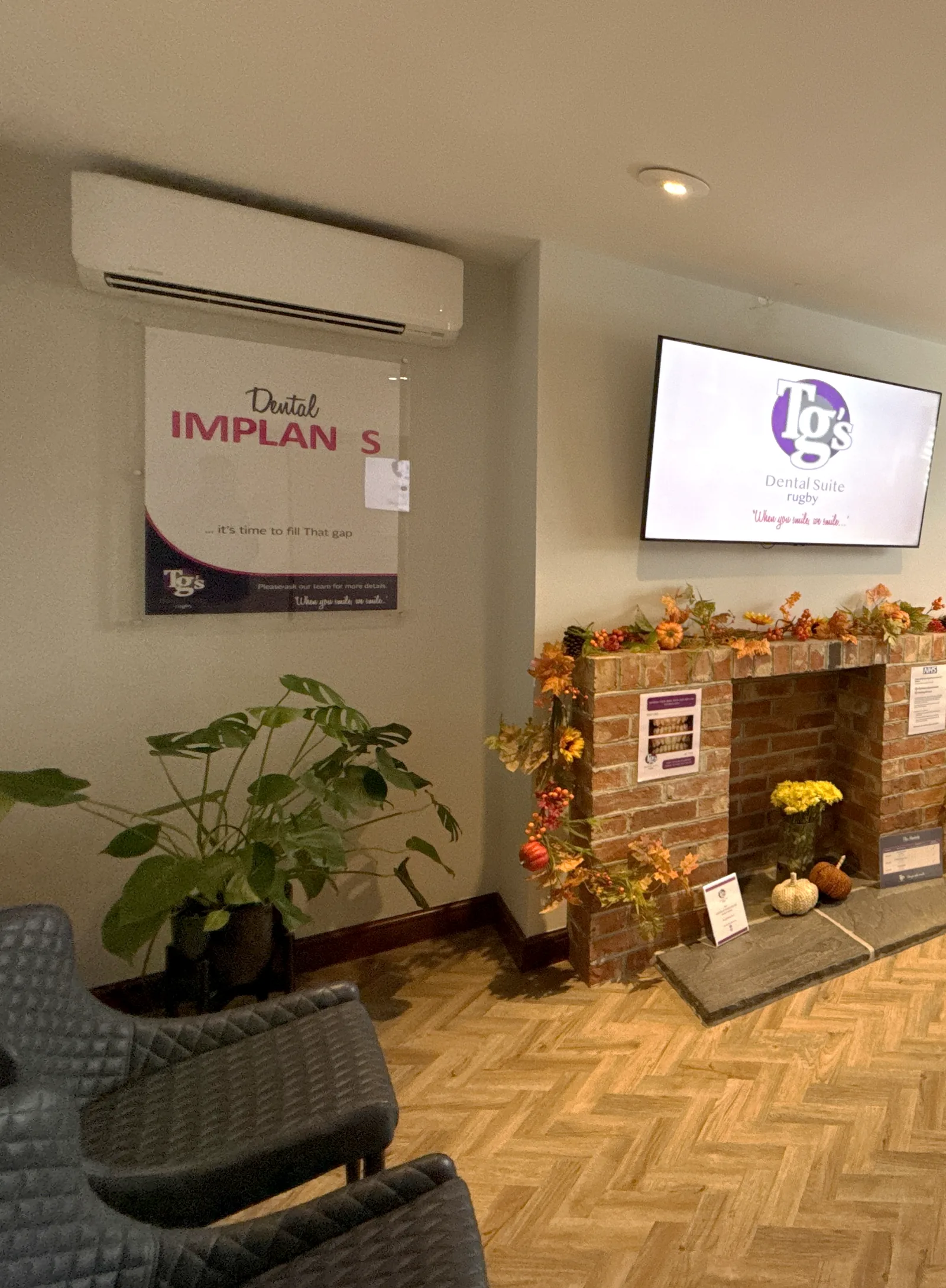 The Rugby waiting room, with seating beside the brick fireplace and the practice screen above it