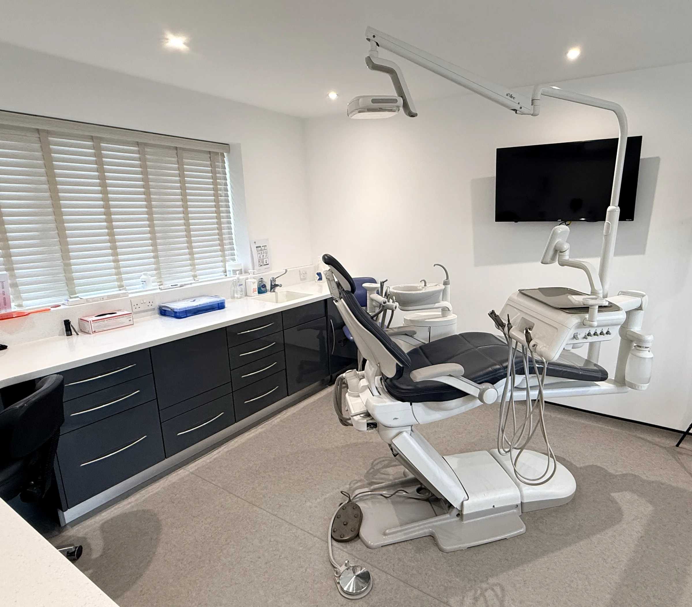 A treatment room at Scraptoft, with the chair, overhead light, wall screen and dark cabinetry